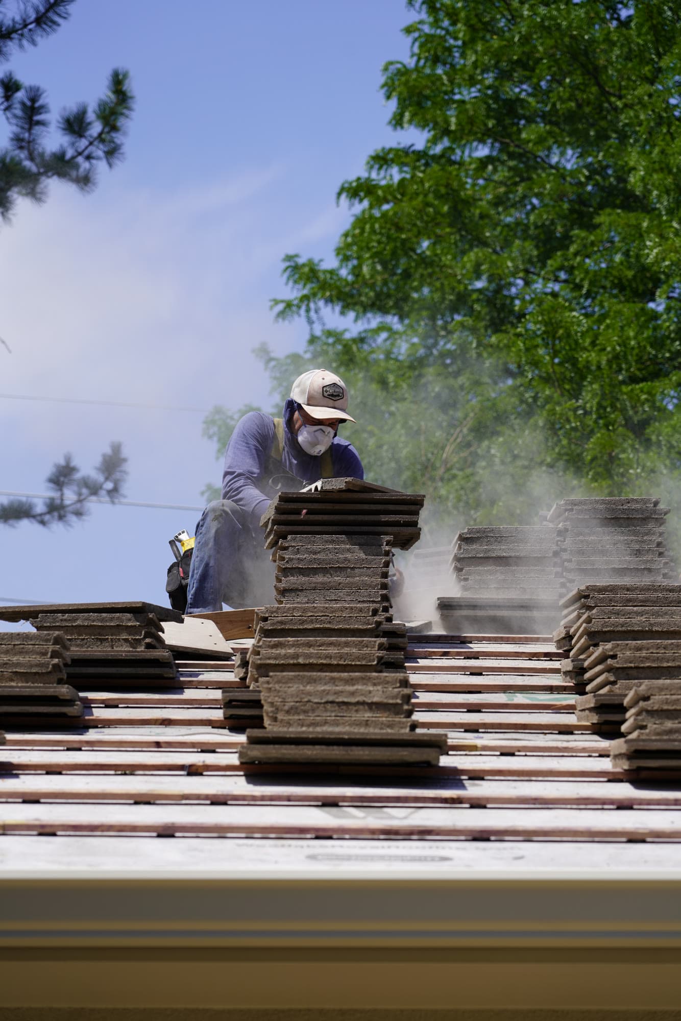 Roofer carrying tile up to a re-roof in progress