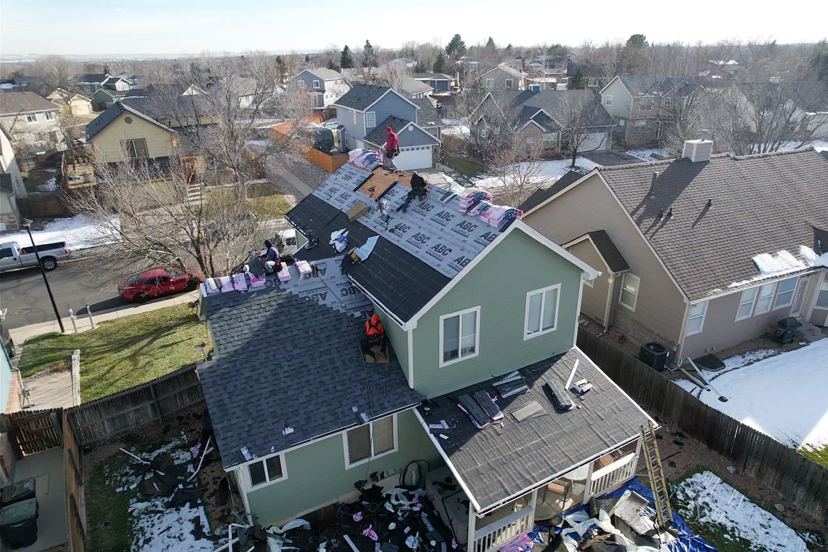 Crew mid-installation on a residential roof, aerial view