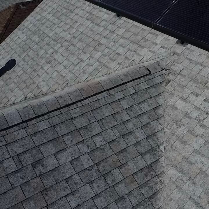 Close-up of storm-damaged shingles with a separated ridge cap, documented on a roof inspection